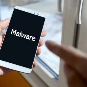 a person sees a white inscription on a black smartphone display that holds in his hand malware t20 kRjx8E