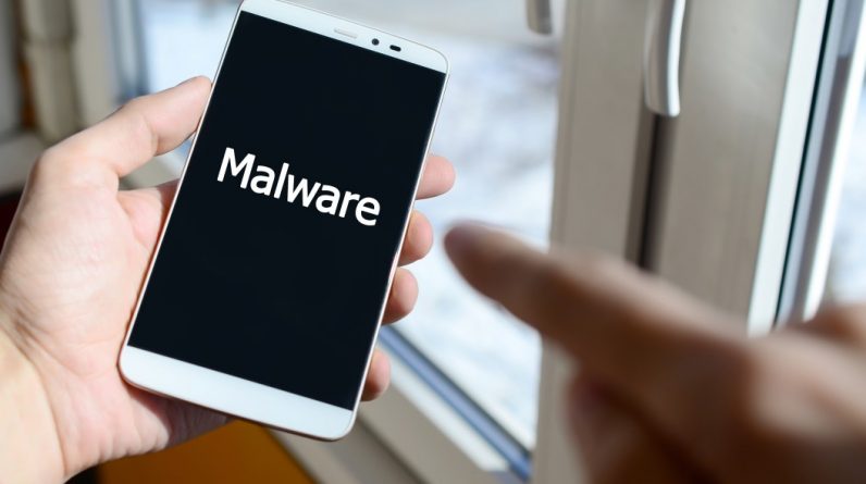 a person sees a white inscription on a black smartphone display that holds in his hand malware t20 kRjx8E