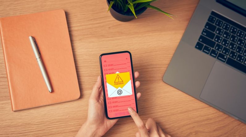 concept of cyber crime hand holding smartphone and show malware screen that comes with email hack t20 AVWnlV
